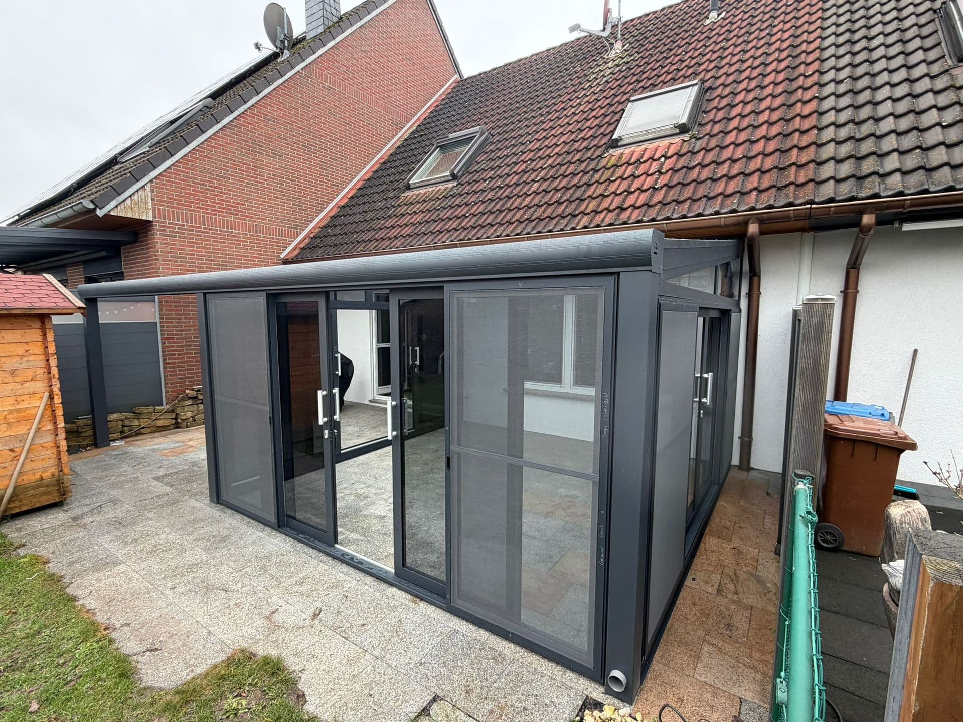 Gerealiseerde antraciet aluminium veranda met glazen dakplaten, bovenaanzicht vanuit terras